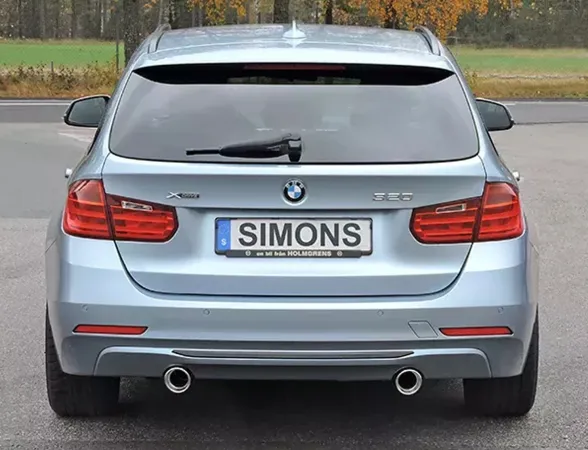 Vista posteriore di una BMW F31 320i estate di colore azzurro con sistema di scarico sportivo duplex. Targa con scritta Simons. I terminali dell'impianto di scarico sono disposti a destra e a sinistra. Sono visibili le luci posteriori e il logo BMW.