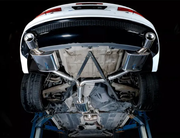 Vista dal basso di un'Audi A4 (B8) bianca su un ponte sollevatore, con silenziatore sportivo Duplex L+R Simons in acciaio inox. Terminali duplex 1x100 mm a sinistra e a destra; scarico in inox.